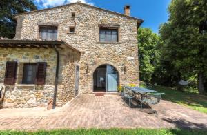a stone house with a table in front of it at Agriturismo La Collina Dei Lecci in San Gimignano