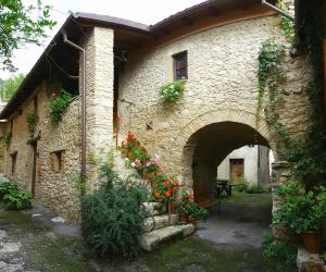 a stone house with flowers on the side of it at Casa Vacanze Sotto l'Arco in Barete