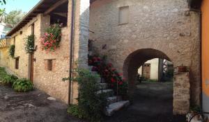a stone building with a staircase with red flowers at Casa Vacanze Sotto l'Arco in Barete