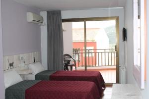 a hotel room with two beds and a balcony at Hotel el Pino in Teror