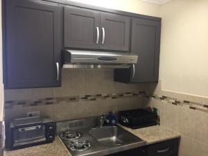 a kitchen with black cabinets and a sink and a stove at Seaside Motel in Redondo Beach