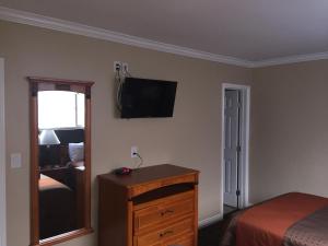 a bedroom with a bed and a dresser with a television on the wall at Seaside Motel in Redondo Beach