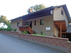 uma casa de tijolos com um alpendre e um deque em Ferienwohnung am Zeitenweg em Windeck