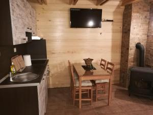 a kitchen with a table and a television on a wall at Lodge Nagramak in Sekulić 