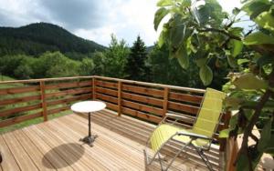 una terraza de madera con una silla y una mesa. en Gîte du Poirier, en Le Tholy