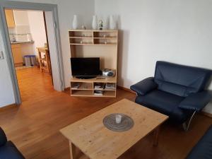 ein Wohnzimmer mit einem Sofa, einem Tisch und einem TV in der Unterkunft Weingut-Klosterhof in Brauneberg