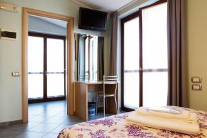 sypialnia z łóżkiem, biurkiem i oknami w obiekcie Albergo Verdi w mieście Novi Ligure