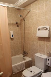 a bathroom with a toilet and a shower and a tub at Hotel el Pino in Teror