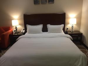 a bedroom with a large white bed with two lamps at Asfar Plaza Hotel & Apartments in Riyadh +13 photos