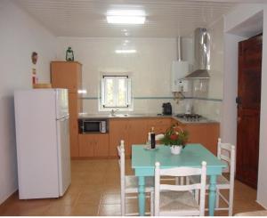uma cozinha com uma mesa azul e um frigorífico branco em Casa Do Avô In Montejunto em Cadaval