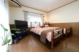 a bedroom with two beds and a flat screen tv at Guesthouse Kimiko in Kasagicho