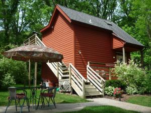 a red house with a table and chairs and an umbrella at Farmers Guest House in Galena