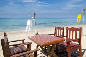 - une table et des chaises en bois sur la plage dans l'établissement Nature Beach Resort, Koh Lanta, à Ko Lanta