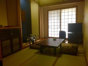 a living room with a table and a window at Ryokan Yamanoyu in Minamioguni