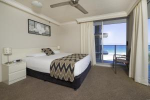 una camera da letto con un letto e una porta scorrevole in vetro di Sunbird Beach Resort Gold Coast a Gold Coast