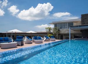 a swimming pool with lounge chairs and a building at Solia Legian Bali in Legian