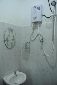 a bathroom with a shower with a sink and a mirror at Wave Langkawi Inn in Pantai Cenang
