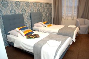 pokój hotelowy z dwoma łóżkami i krzesłem w obiekcie Acwador w mieście Pleszew