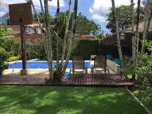 a backyard with two chairs and a swimming pool at Suítes da Piscina in Ilhabela