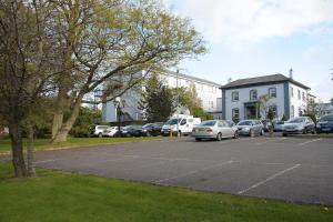a parking lot with cars parked in front of a building at Drummond Hotel in Ballykelly