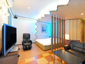 Zimmer mit einem Bett, einem TV und einem Sofa in der Unterkunft Hotel.COM (Adult Only) in Nagoya