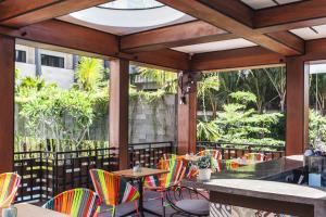 eine Terrasse mit bunten Stühlen, Tischen und Fenstern in der Unterkunft Solia Legian Bali in Legian