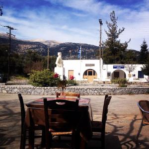 a table with chairs and a statue in front of a building at Platanos Rooms in Anopoli Sfakion