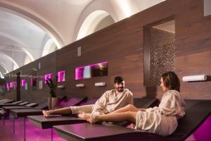 a man and a woman sitting on benches in a building at Grand Hotel Sava Superior in Rogaška Slatina