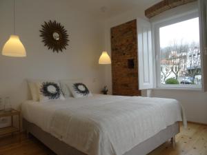 a bedroom with a large white bed with a window at Alojamentos Casa Facha Menta in Portalegre