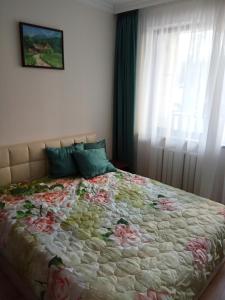 a bedroom with a bed with a floral comforter and a window at Denitsa Apartment in Borovets