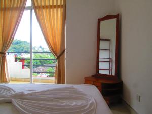 een slaapkamer met een bed, een spiegel en een raam bij Kandyan Sweet Villa in Kandy