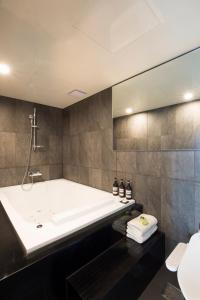 a bathroom with a tub and a sink at Hotel Foret Premier Nampo in Busan