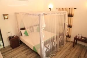 a bed with a canopy in a room at Villa Pinnawala & Restaurant in Pinnawala