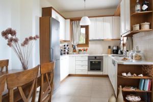 a kitchen with white appliances and a table and chairs at Natica Mare Villas in Xerokampos