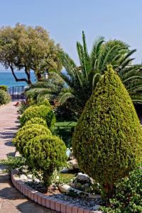 a garden with bushes and trees and the ocean at Karfas Bay View in Karfas