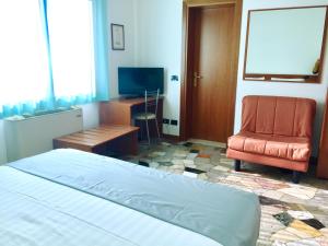 - une chambre avec un lit, une chaise et une télévision dans l'établissement Albergo Isetta, à Grancona