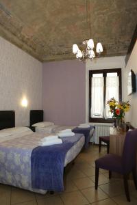 フィレンツェにあるAdelaide Houseのベッド3台、テーブル、椅子が備わる客室です。