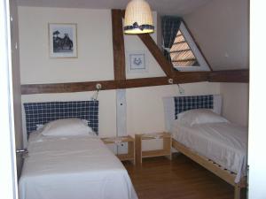 een slaapkamer met 2 bedden en een balkenplafond bij GÎte rue de l'Ange in Hunspach