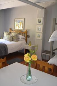 a vase with flowers on a table in a bedroom at Rooiheuwel Cottage in Wellington