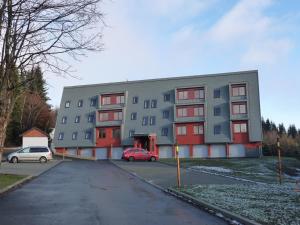 ein Gebäude mit einem roten Auto, das davor geparkt ist in der Unterkunft Apartmány Racek in Ostružná