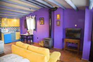 sala de estar con paredes de color púrpura, sofá y TV en Apartamentos La Iguana, en Hervás