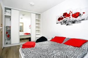 a bedroom with a bed with red pillows at Dream Apartment in Świnoujście
