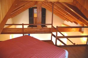 Camera mansardata con letto e travi in legno. di Casa Angelino a Cannobio