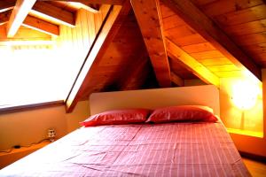 a bed with red pillows in a room with an attic at Casa Angelino in Cannobio