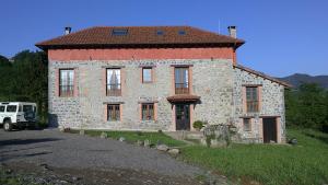 a large stone house with a red roof at El Conventu del Asturcon in Lago