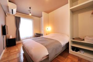 a bedroom with a large bed and a window at Coco Stay Nishikawaguchi Ekimae in Kawaguchi