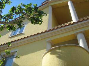 een geel gebouw met twee ramen en een boom bij Jacqueline Apartment in Pula