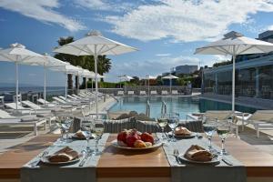 a table with a plate of fruit and wine glasses at Saint George Hotel in Chrissi Akti
