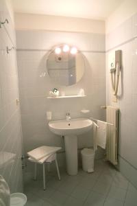 Baño blanco con lavabo y espejo en Albergo Sapori, en Tolè