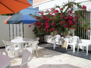 un patio con mesas y sillas blancas y flores rosas en Hotel La Fontana en Termas de Río Hondo